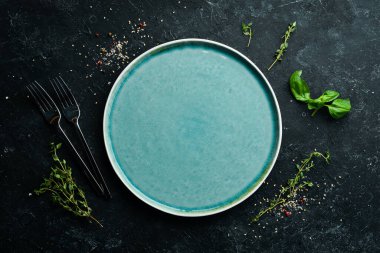 Siyah taşlı arka planda sebzeli ve baharatlı mavi tabak. Üst Manzara. Kırsal biçim.