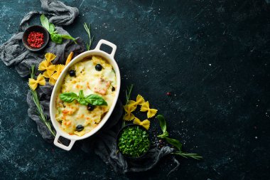 Siyah taştan bir arka planda somon ve peynirli fırında makarna. Üst Manzara. Kırsal biçim.