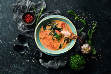 Deniz ürünleri çorbası. Siyah taşlı arka planda karidesli domates çorbası. Üst Manzara. Kırsal biçim.