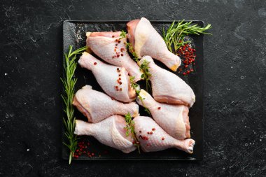 Siyah taşlı arka planda baharatlı çiğ tavuk budu. - Et. Üst Manzara. Kırsal biçim.