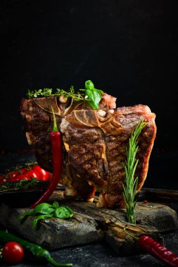 Siyah arka planda baharatlı ve otlu iki sulu ızgara biftek. Üst Manzara. Kırsal biçim.
