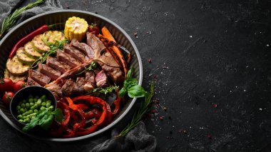 Kemiğin üzerinde ızgara sebze ve baharatla dilimlenmiş biftek. Biftek. Üst Manzara. Kırsal biçim.