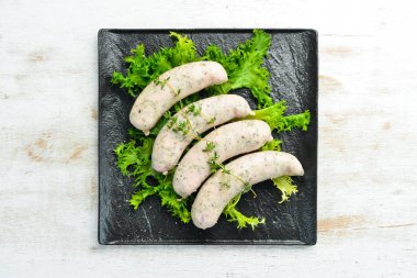 Siyah bir tabakta kekik ve baharatla çiğ sosis. Üst Manzara. Eski arkaplan, köy tarzı.