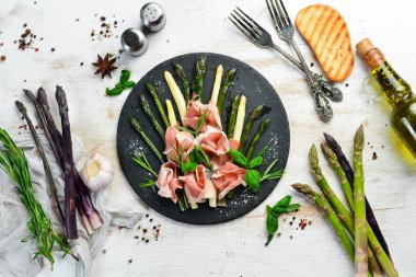 Haşlanmış kuşkonmaz ve siyah taş tabakta baharatlı jambon. Üst Manzara. Metnin için boş yer.