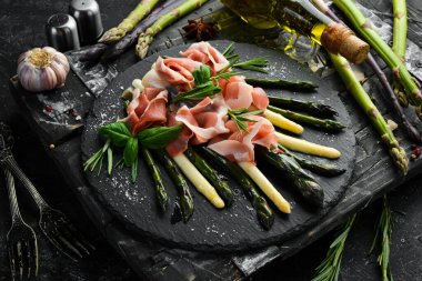 Haşlanmış kuşkonmaz ve siyah taş tabakta baharatlı jambon. Üst Manzara. Metnin için boş yer.