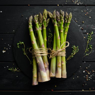 Siyah taştan bir arka planda taze yeşil kuşkonmaz. Sağlıklı yiyecekler. Üst görünüm, ücretsiz kopyalama alanı.