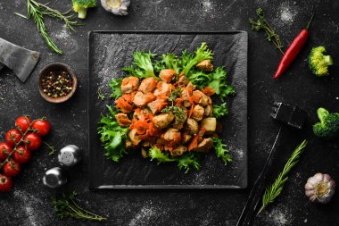 Siyah taş bir tabakta bira içinde sebzelerle pişirilmiş domuz eti. Üst Manzara. Siyah bir arkaplanda.