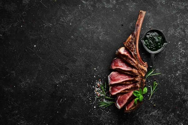 Kemiğe baharat ve otlarla dilimlenmiş Tomahawk bifteği. Üst Manzara. Boş kopyalama alanı.