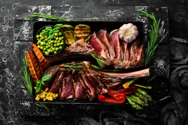 Kemiğe biftek. Sebze ve baharatlı iki sulu dana biftek. Siyah bir arka planda. Üst Manzara. Boş kopyalama alanı.