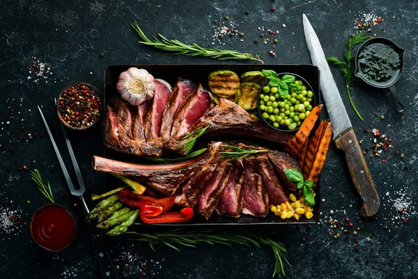 Kemiğe biftek. Sebze ve baharatlı iki sulu dana biftek. Siyah bir arka planda. Üst Manzara. Boş kopyalama alanı.