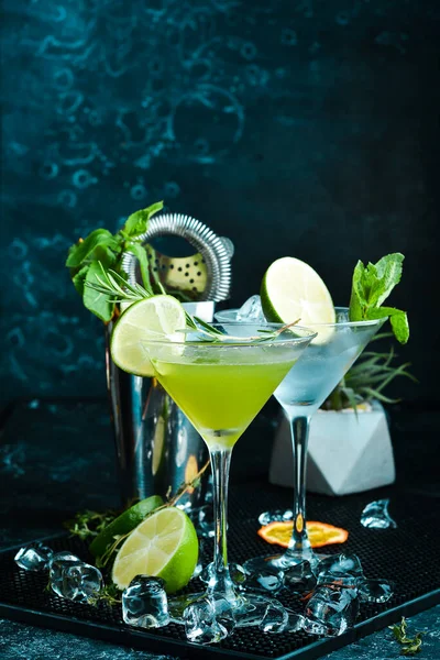 Green alcoholic cocktail with lime and rosemary. On a black stone background. Menu bar.