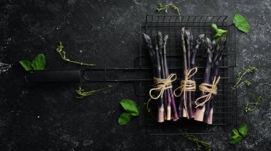 Siyah taştan bir arka planda çiğ organik mor kuşkonmaz. Sağlıklı yiyecekler. Üst görünüm, ücretsiz kopyalama alanı.