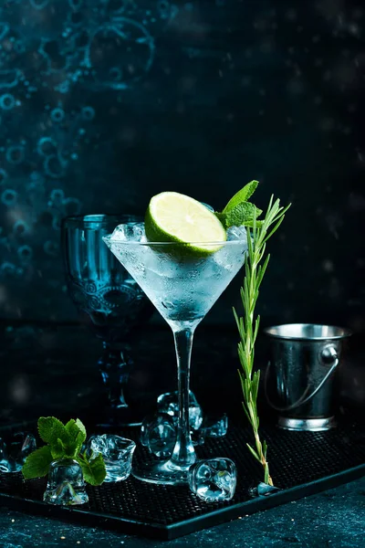 Cocktail with lime and rosemary. On a black stone background. Menu bar.