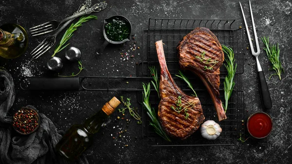 Dva Pečené Hovězí Steaky Kosti Kořením Bylinkami Černém Kamenném Pozadí — Stock fotografie