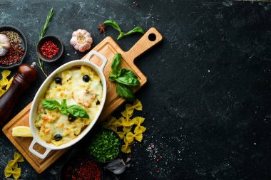 Siyah taştan bir arka planda somon ve peynirli fırında makarna. Üst Manzara. Kırsal biçim.