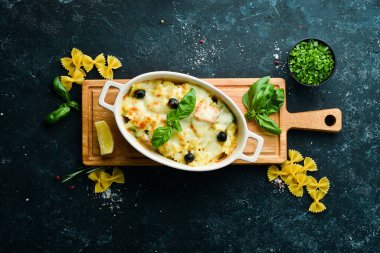 Siyah taştan bir arka planda somon ve peynirli fırında makarna. Üst Manzara. Kırsal biçim.