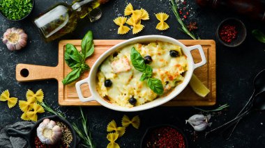 Siyah taştan bir arka planda somon ve peynirli fırında makarna. Üst Manzara. Kırsal biçim.