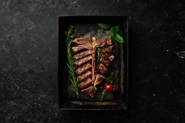 Siyah arka planda metal bir tencerede baharatlı ızgara biftek. Üst Manzara. Kırsal biçim.