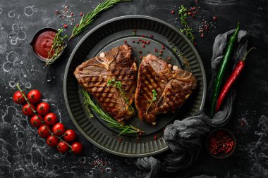 Siyah arka planda metal bir tencerede baharatlı ızgara biftek. Üst Manzara. Kırsal biçim.