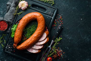 Taze pişmiş sosis. Siyah taşlı arka planda salam. Üst Manzara. Metin için boş alan.