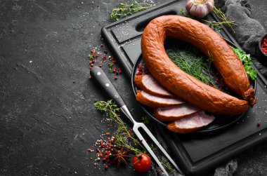 Taze pişmiş sosis. Siyah taşlı arka planda salam. Üst Manzara. Metin için boş alan.