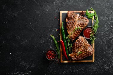 Siyah arka planda baharatlı ve otlu iki sulu ızgara biftek. Üst Manzara. Kırsal biçim.