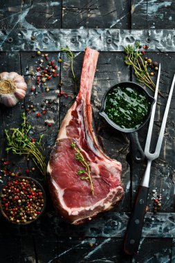 Tomahawk bifteği. Siyah arka planda çiğ biftek. Üst Manzara. Boş kopyalama alanı.
