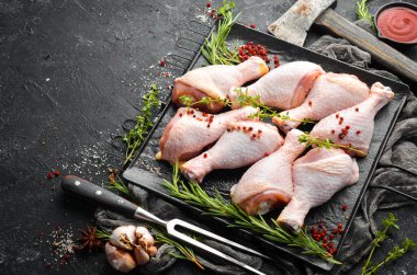 Siyah taşlı arka planda baharatlı çiğ tavuk budu. - Et. Üst Manzara. Kırsal biçim.