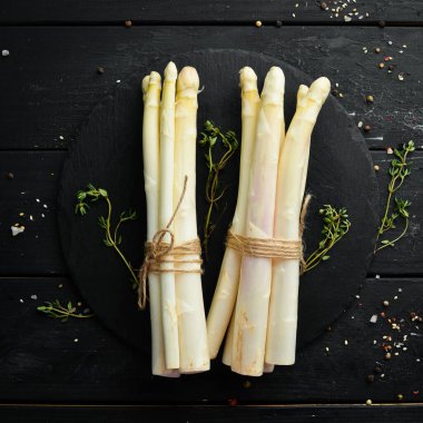 Siyah taşlı arka planda çiğ beyaz kuşkonmaz. Sağlıklı yiyecekler. Üst Manzara. Metnin için boş yer.