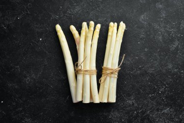 Siyah taşlı arka planda çiğ beyaz kuşkonmaz. Sağlıklı yiyecekler. Üst Manzara. Metnin için boş yer.