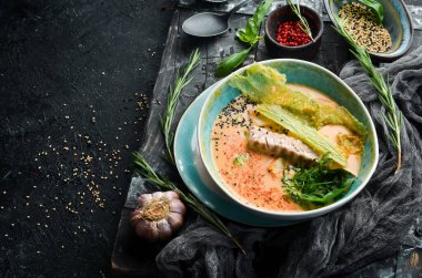 Deniz ürünleri çorbası. Kaymaklı ton balığı çorbası, siyah taşlı arka planda bir kasede. Üst Manzara. Kırsal biçim.