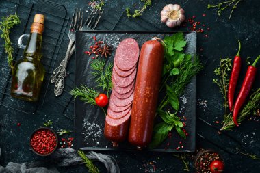 Taze biberiye ve baharatlı salam. Siyah taştan bir arka planda. Üst Manzara. Metin için boş alan.