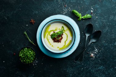 Sağlıklı yiyecekler. Kremalı çorba, domuz pastırması ve fesleğenli siyah taşlı bir tabakta. Üst Manzara. Kırsal biçim.