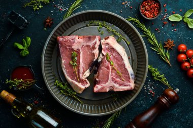 Siyah taştan bir arka planda metal bir pişirme kabında çiğ biftek. Üst Manzara. Kırsal biçim.