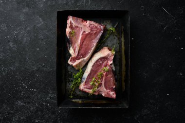 Siyah taştan bir arka planda metal bir pişirme kabında çiğ biftek. Üst Manzara. Kırsal biçim.