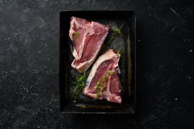 Siyah taştan bir arka planda metal bir pişirme kabında çiğ biftek. Üst Manzara. Kırsal biçim.