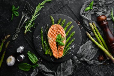 Pişmiş kuşkonmaz ve siyah taş tabakta baharatlı somon bifteği. Üst Manzara. Metnin için boş yer.