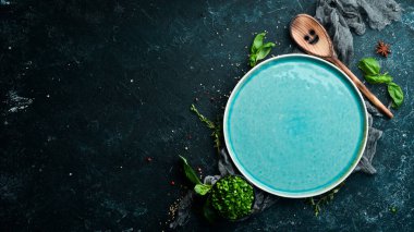 Siyah taşlı arka planda sebzeli ve baharatlı mavi tabak. Üst Manzara. Kırsal biçim.