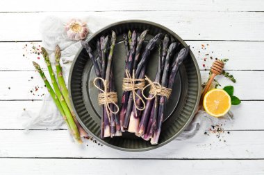 Beyaz ahşap arka planda çiğ kuşkonmaz demeti. Sağlıklı yiyecekler. Üst görünüm, ücretsiz kopyalama alanı.