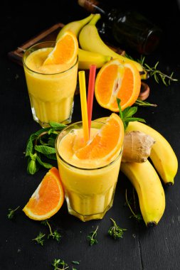 Meyve püresi. Muz, portakal ve zencefilli içecek. Sağlıklı içecekler. Üst Manzara. Siyah bir arkaplanda.