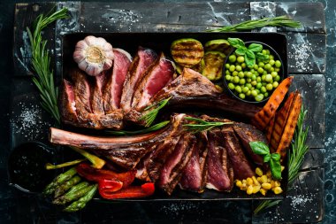 Kemiğe biftek. Sebze ve baharatlı iki sulu dana biftek. Siyah bir arka planda. Üst Manzara. Boş kopyalama alanı.