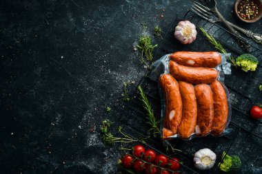Vakum ambalajında füme sosis. Üst Manzara. Siyah bir arkaplanda.