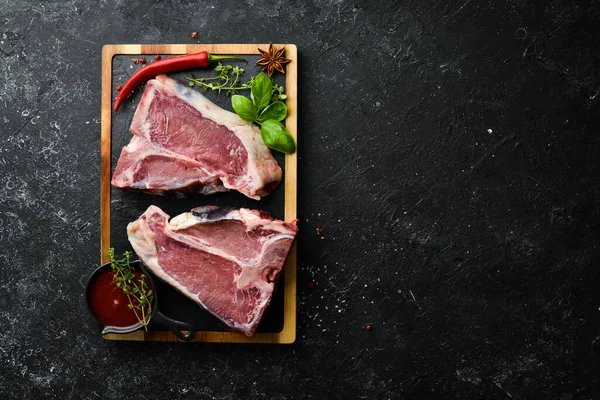 Syrový Steak Kosti Kořením Bylinkami Dřevěné Desce Horní Pohled Černém — Stock fotografie