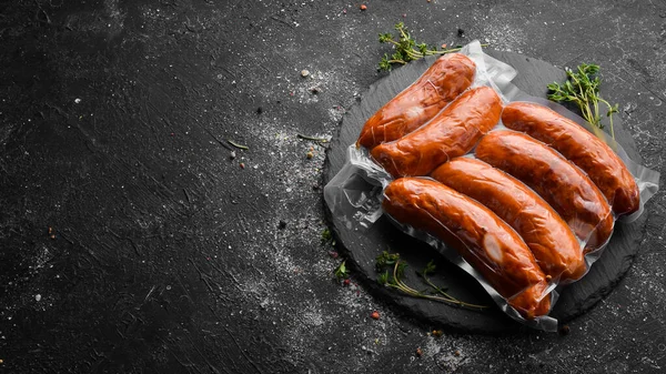 Smoked sausages in vacuum packaging. Top view. On a black background.