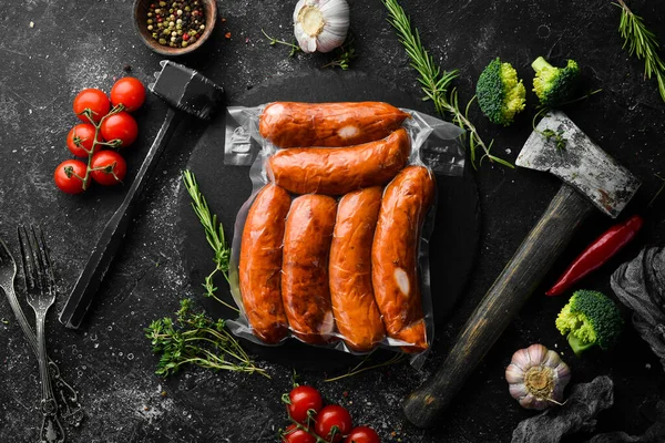 Smoked sausages in vacuum packaging. Top view. On a black background.