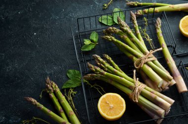 Siyah taştan bir arka planda taze yeşil kuşkonmaz. Sağlıklı yiyecekler. Üst görünüm, ücretsiz kopyalama alanı.
