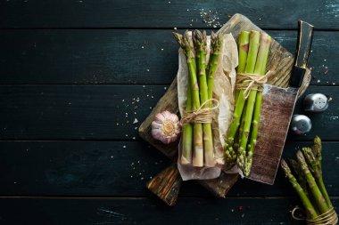 Siyah taştan bir arka planda taze yeşil kuşkonmaz. Sağlıklı yiyecekler. Üst görünüm, ücretsiz kopyalama alanı.