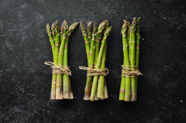 Siyah taştan bir arka planda taze yeşil kuşkonmaz. Sağlıklı yiyecekler. Üst görünüm, ücretsiz kopyalama alanı.