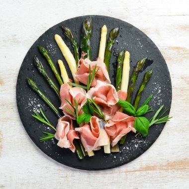 Haşlanmış kuşkonmaz ve siyah taş tabakta baharatlı jambon. Üst Manzara. Metnin için boş yer.