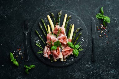 Haşlanmış kuşkonmaz ve siyah taş tabakta baharatlı jambon. Üst Manzara. Metnin için boş yer.